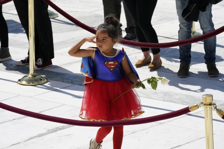 A child in a Supergirl costume pays respects as Ruth Bader Ginsburg lies in repose at the top of the front steps of the Supreme Court building. Alex Brandon/Pool via REUTERS